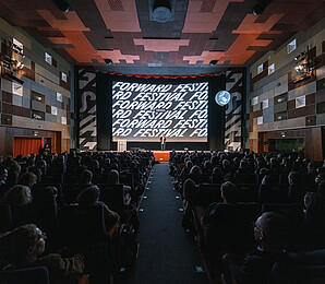 Cinema screen of the Gartenbau Kino with Forward Festival inscription and full cinema hall
