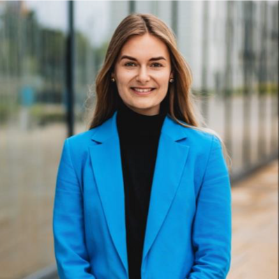 Blond women in blue jacket, smiling into the camera.