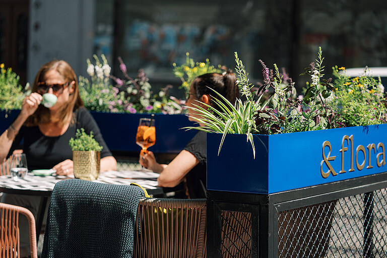 Outdoor dining area &flora Two people are sitting in the outdoor dining area with a drink