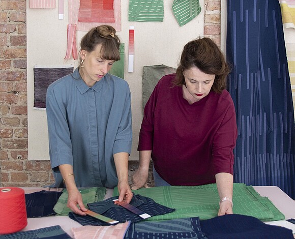 two textile designers looking at colourful fabrics on a table