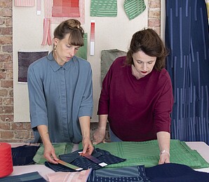 two textile designers looking at colourful fabrics on a table