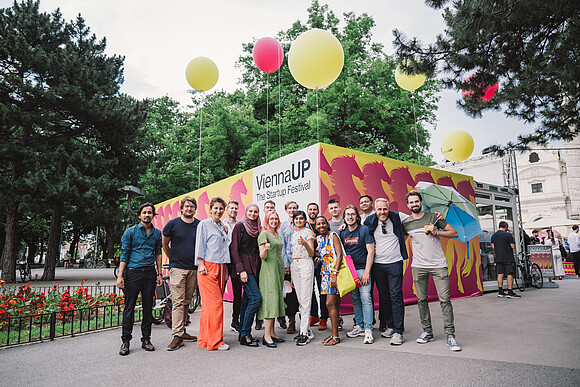 Crowd in front of a container with the ViennaUP logo and balloons on Karlsplatz in Vienna.