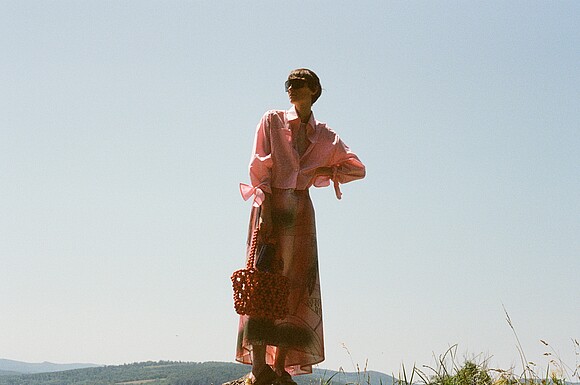 Woman wearing a salmon-coloured patterned dress in nature.
