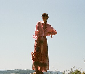 Woman wearing a salmon-coloured patterned dress in nature.