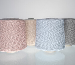 Spools of yarn dyed with the Vienna Colours, in pastel shades of pink and blue.