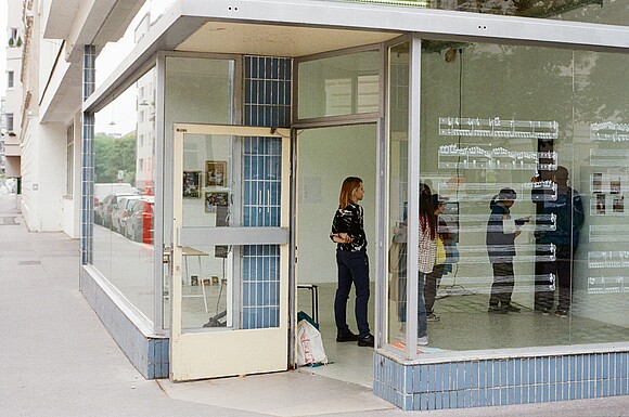 People in an art space, a shopfront with a glass façade