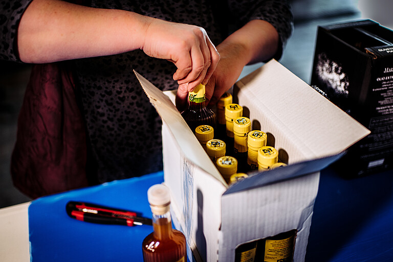 Person arranges vinegar bottles in a cardboard box