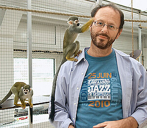 [Translate to English:] EIn Mann im weißen Kittel kümmert sich liebevoll um zwei Äffchen