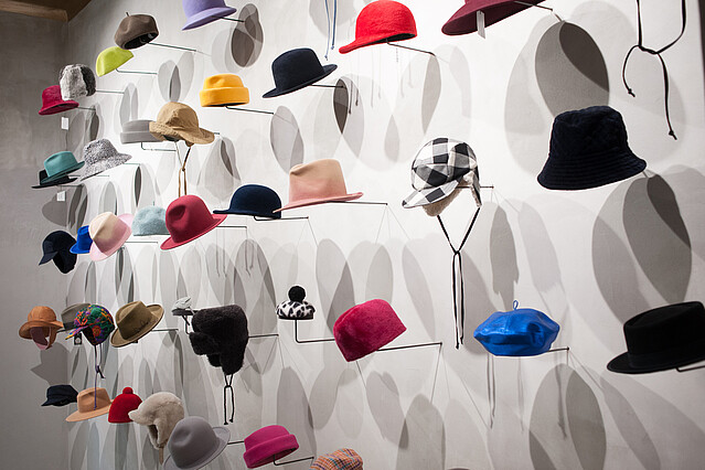 Hutmode Biester: Viele unterschiedliche Hüte sind an einer Wand ausgestellt