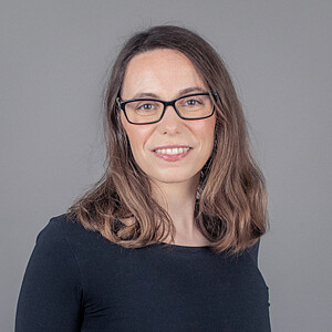 Portrait von Michele Kirchweger, eine Frau mit braunen schulterlangen Haaren und Brille
