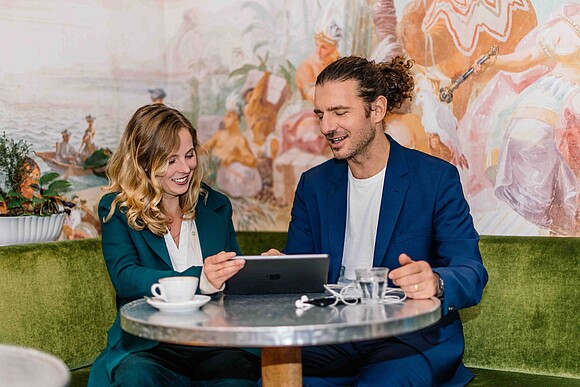 Eine Frau und ein Mann sitzen gemeinsam an einem Tisch und arbeiten an einem Computer