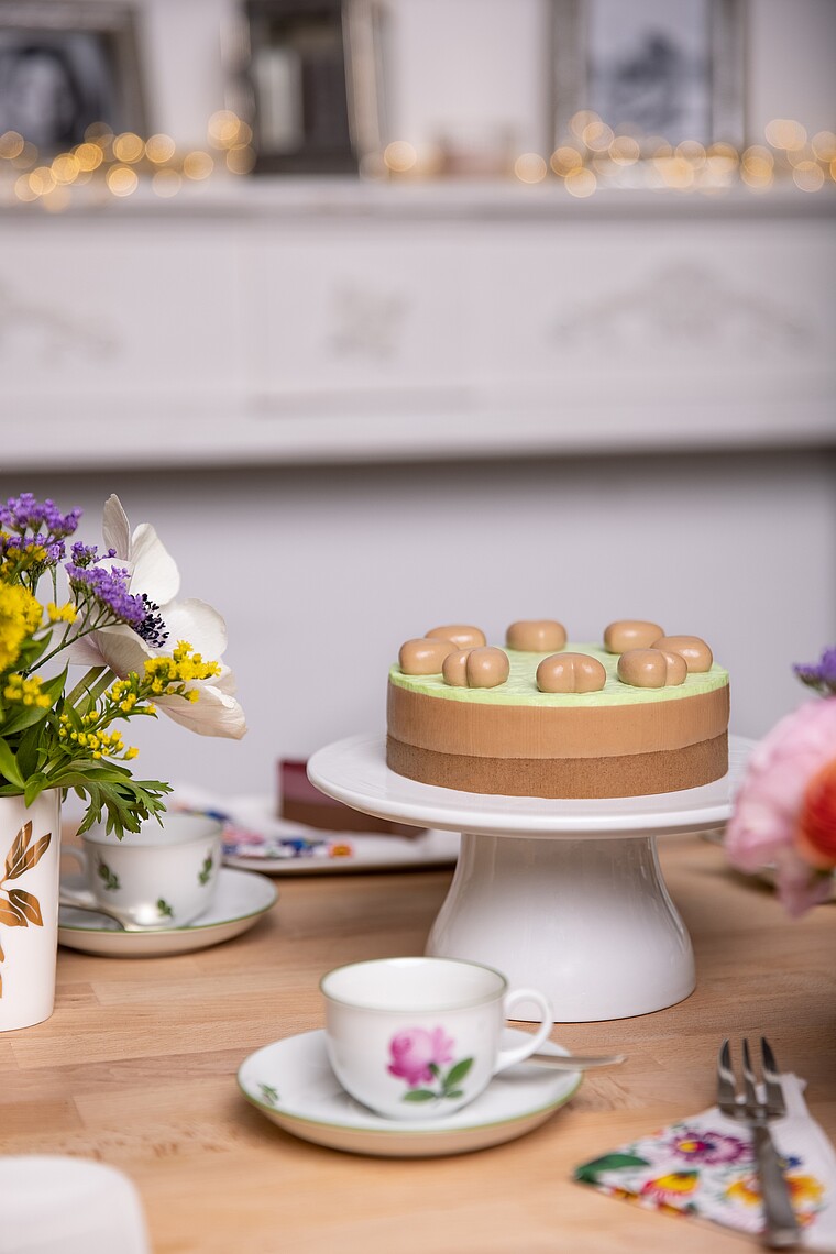 Auf dem Foto sieht man eine Haselnussnougat-Mousse-Torte auf aromatischem Kaffeebiskuit und feine Pistaziencreme.