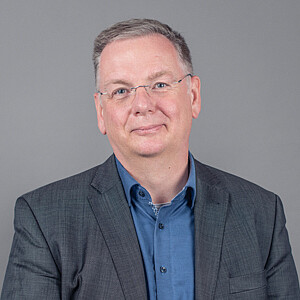 Porträt von Rüdiger Swoboda, ein Mann mit gräulichem Haar und Brille