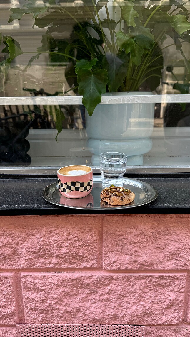 [Translate to English:] Kaffee und Kuchen auf einem Tablett vor dem Geschäft.