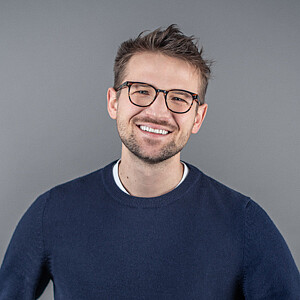 Portrait von John Marquart, ein Mann mit braunen Haaren und Brille