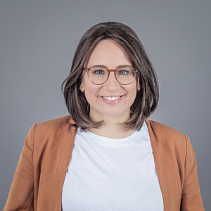 Porträt von Katrin Fahrner, eine Frau mit brünetten, schulterlangen Haaren und Brille